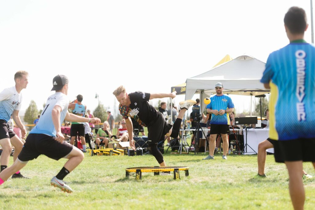 A group of athletes outside playing spikeball around a mini trampoline.