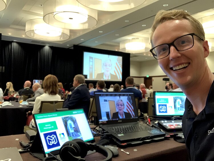 Cooper Brown smiling in front of his tech equipment at a conference.