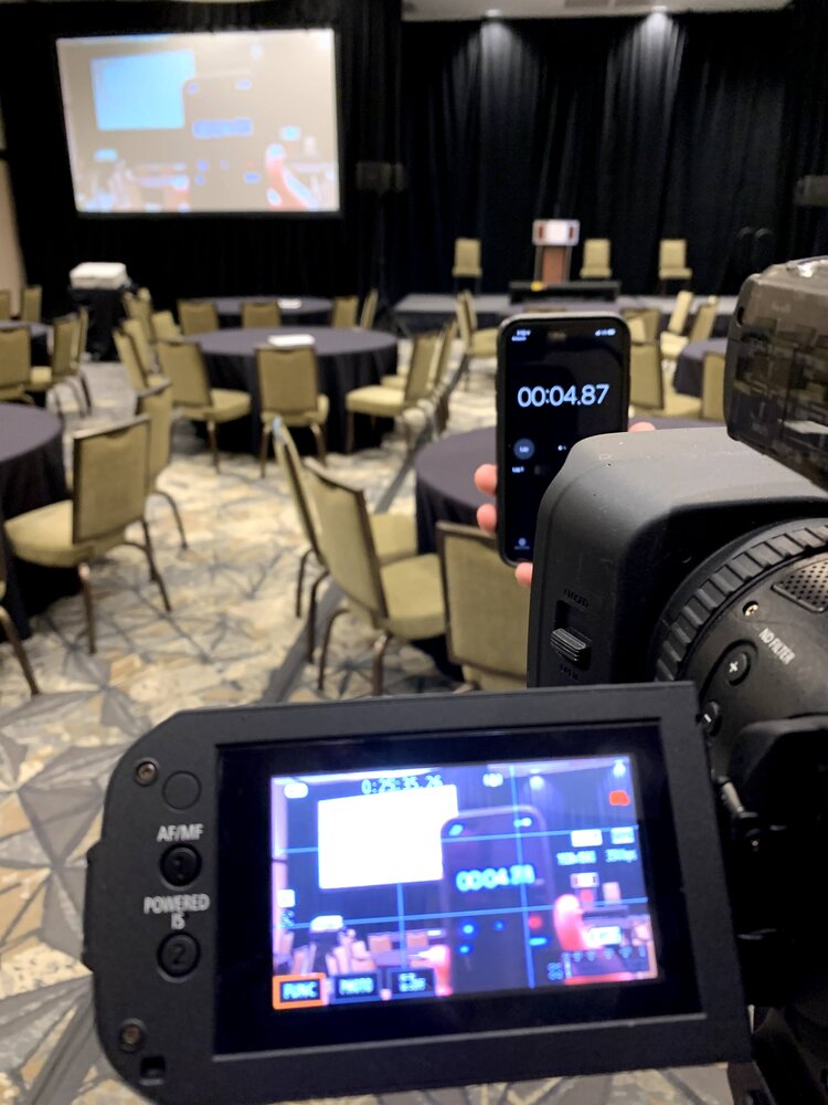 A videocamera and smart phone both test recording an empty conference room.