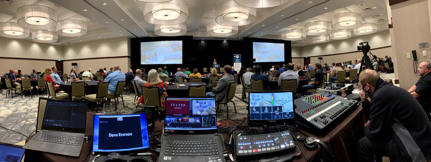 A laptop and other tech equipment monitoring an on-stage discussion.