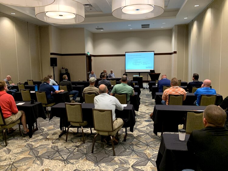 A group of people in a room watching a presentation.