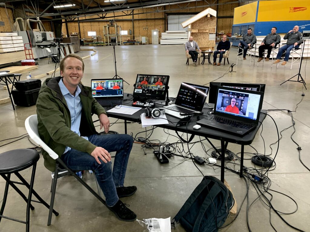 Cooper Brown at a table with a bunch of laptops and monitors in a large open warehouse space.