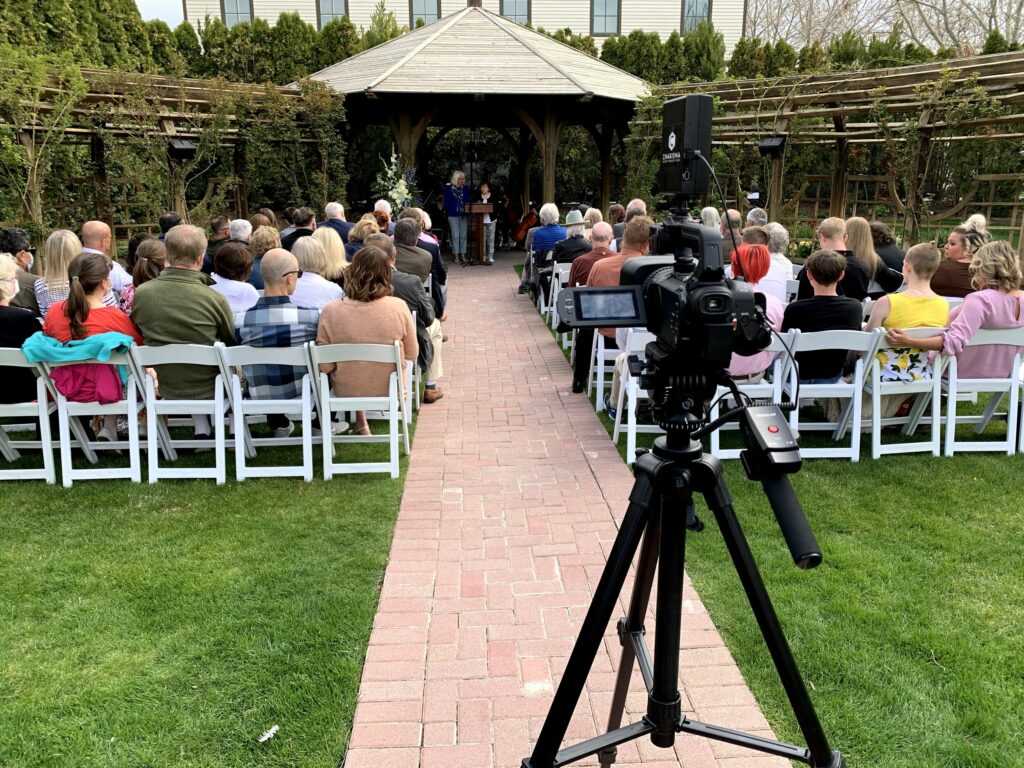 A videocamera livestreaming an outdoor funeral ceremony.