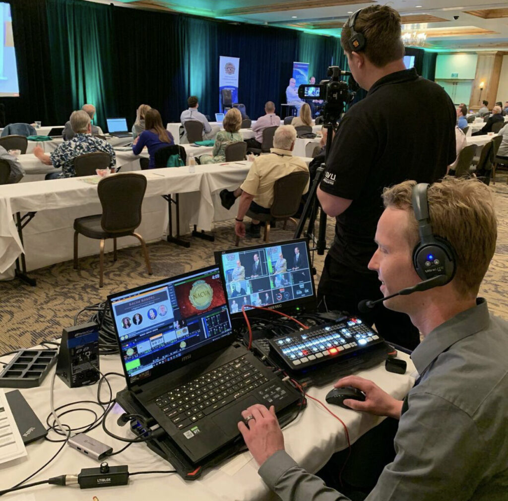 Two engineers monitoring and filming an event.