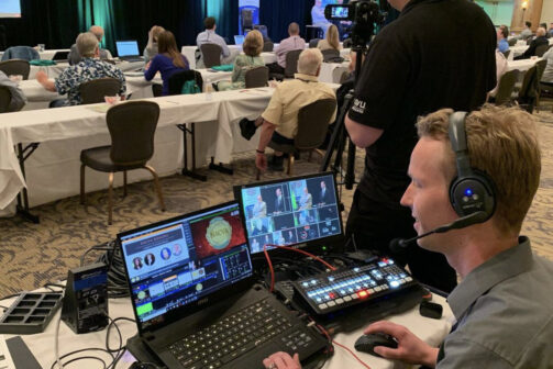 Two engineers monitoring and filming an event.