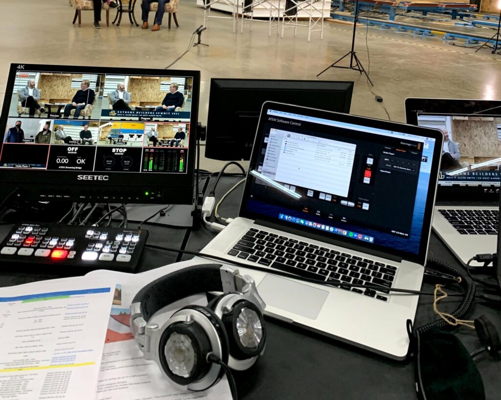 Two laptops, monitors, and headphones on a table in a large, open indoor space.