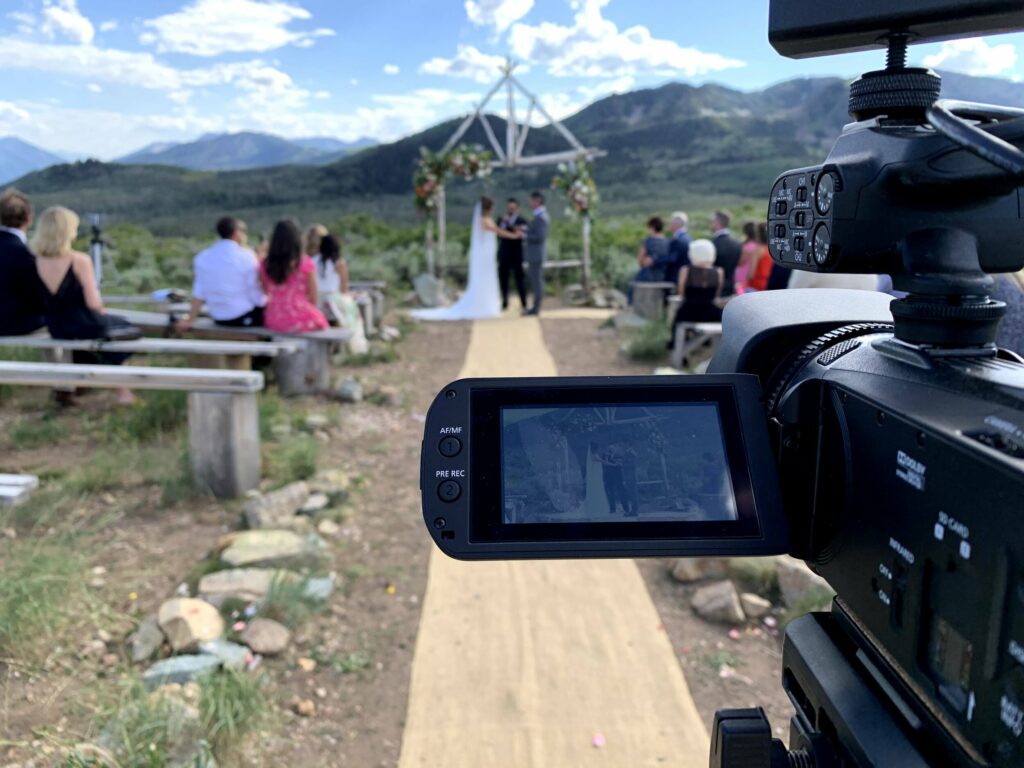 The flip screen of a videocamera pointed at a wedding ceremony.